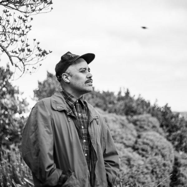 a black and whit portrait of Riki looking our over a block of bush.