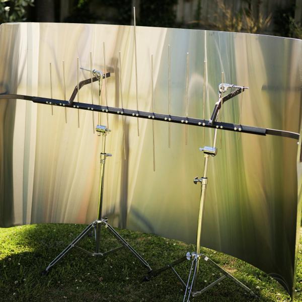 a large sheet of metal is bent into a curve. Inside the curve is a crossbeam with vertical steel bars of different lengths.