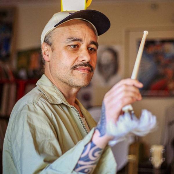 Riki using an albatross bone as a baton to conduct an unseen orchestra.