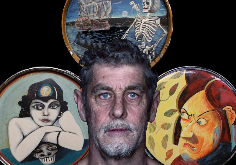 A cropped photo of Anthony Donaldson's face, behind him three of his drumkits each with painted artwork