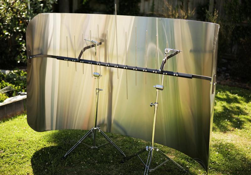 a large sheet of metal is bent into a curve. Inside the curve is a crossbeam with vertical steel bars of different lengths.