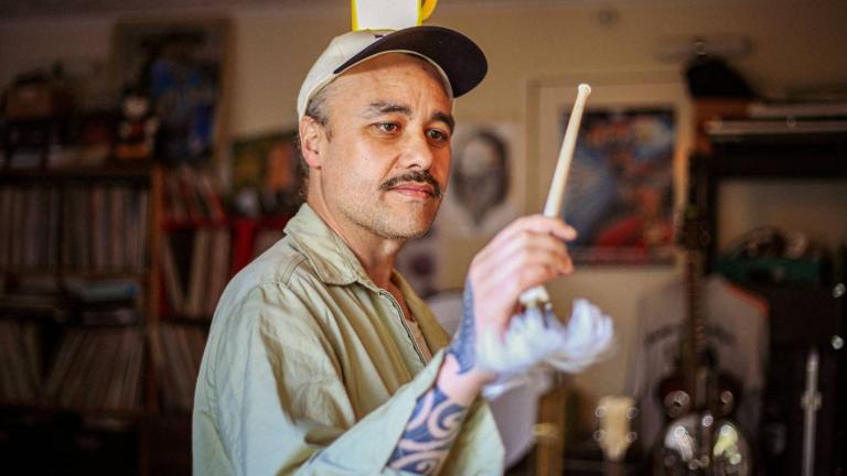 Riki using an albatross bone as a baton to conduct an unseen orchestra.